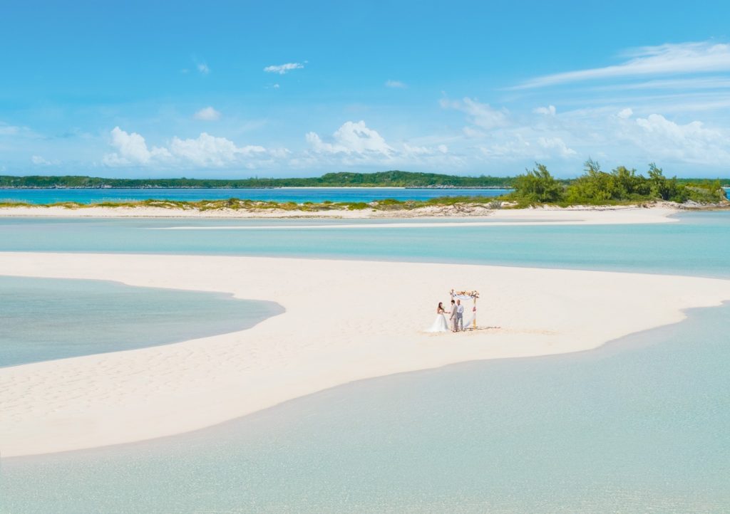 A bride and groom enjoying their wedding ceremony on a sandy beach in the Caribbean.