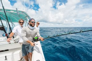 Three men enjoying an all-inclusive fishing adventure aboard a boat in the beautiful Bahamas.