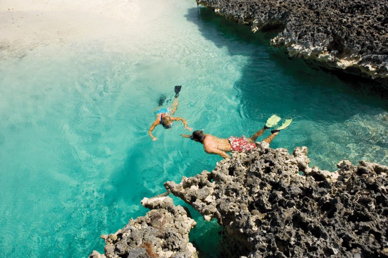 Two people enjoying a snorkeling adventure in the clear blue waters of the Bahamas.
