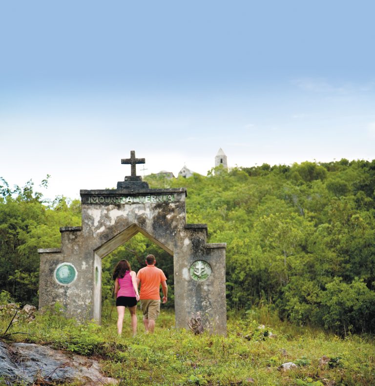 Two people standing in front of an old stone gate on their Bahamas all Inclusive Vacation Packages.