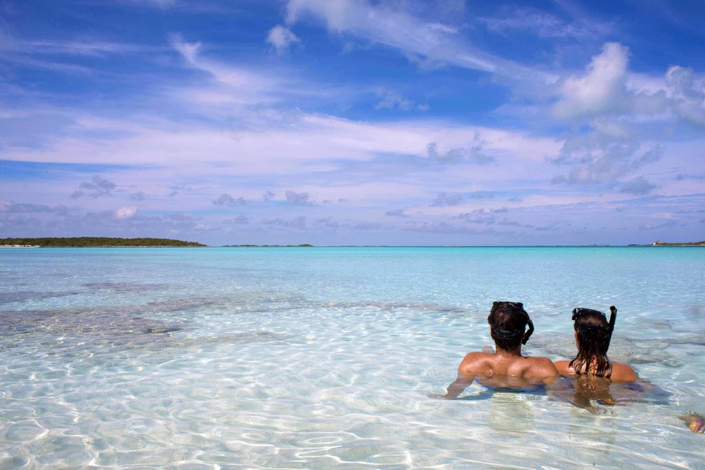 Two people swimming in the clear blue water near Staniel Cay Yacht Club.